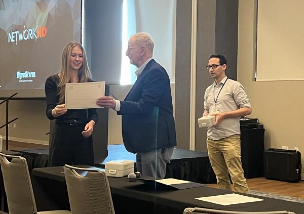 Carly Chandler is awarded her poster prize by organizing committee members David Neilson (U. Antwerp) and Thomas White (UNR)