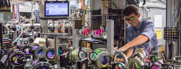 A scientist wearing laser goggles aligns optics on a table